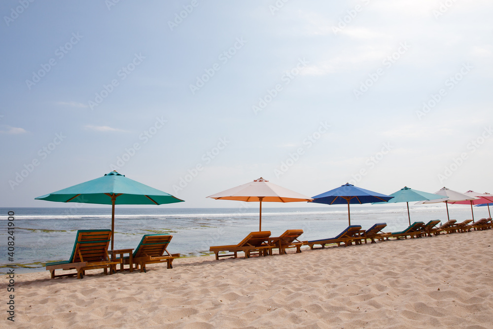 Beach for tourists. Sun loungers and umbrellas on the white sand. Bali island resort, Indonesia.