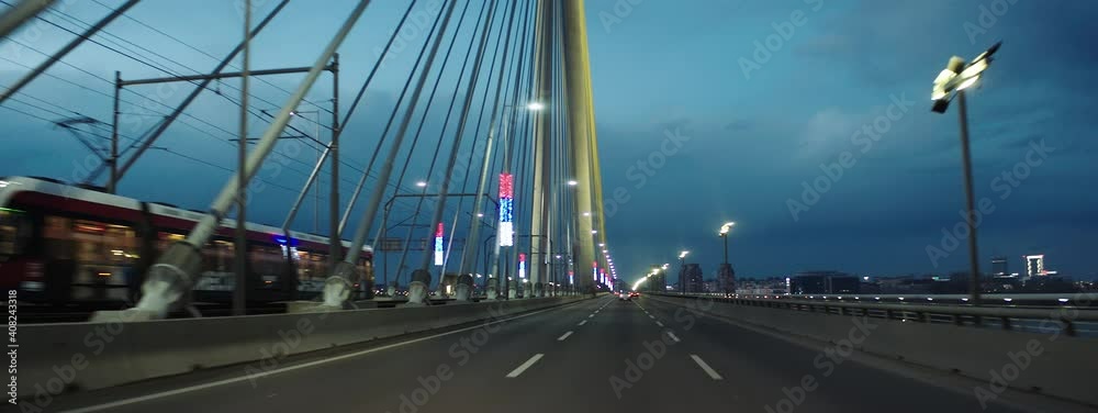 Driving in middle lane of multiple lane road on bridge. Passing modern tram car. Car driver's point of view.