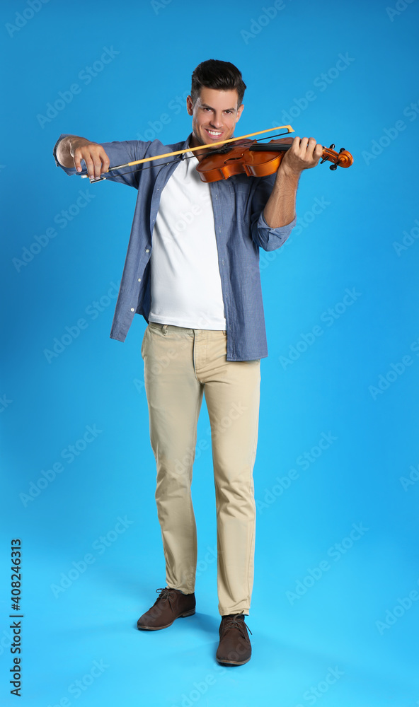 Happy man playing violin on light blue background