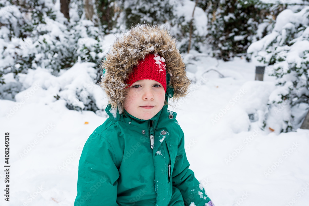 Winter portrait of a girl child playing with snow near the house. Kids in warm clothes having fun in cold weather Winter portrait of a girl child playing with snow near the house. Kids in warm clothes having fun in cold weather