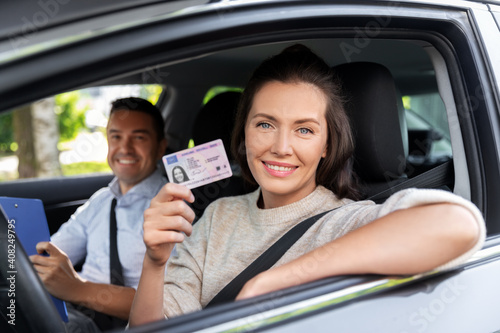 driver courses, exam and people concept - young woman with license and driving school instructor with clipboard in car