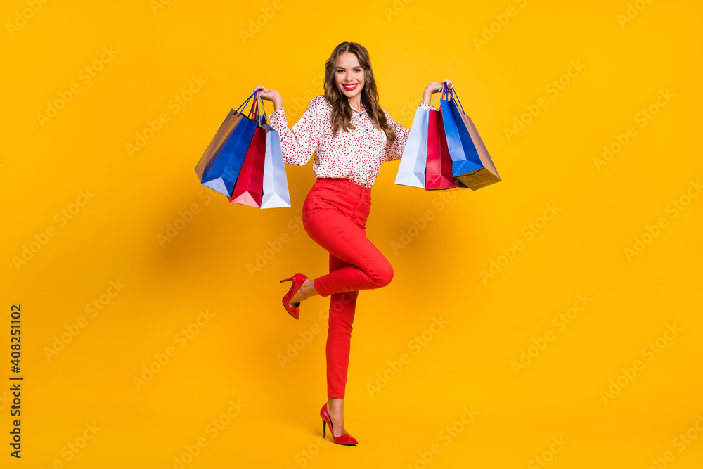 Full body portrait of charming lady arms hold demonstrate bags raise knee isolated on yellow color background Full body portrait of charming lady arms hold demonstrate bags raise knee isolated on yellow color background
