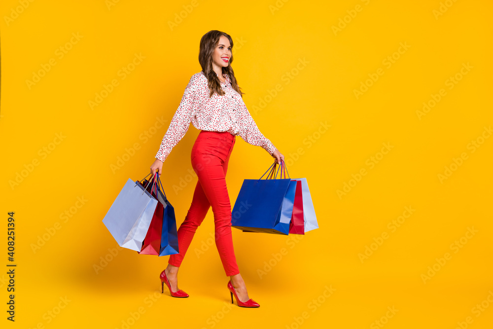 Full size profile portrait of adorable person look empty space walking carry bags isolated on yellow color background Full size profile portrait of adorable person look empty space walking carry bags isolated on yellow color background