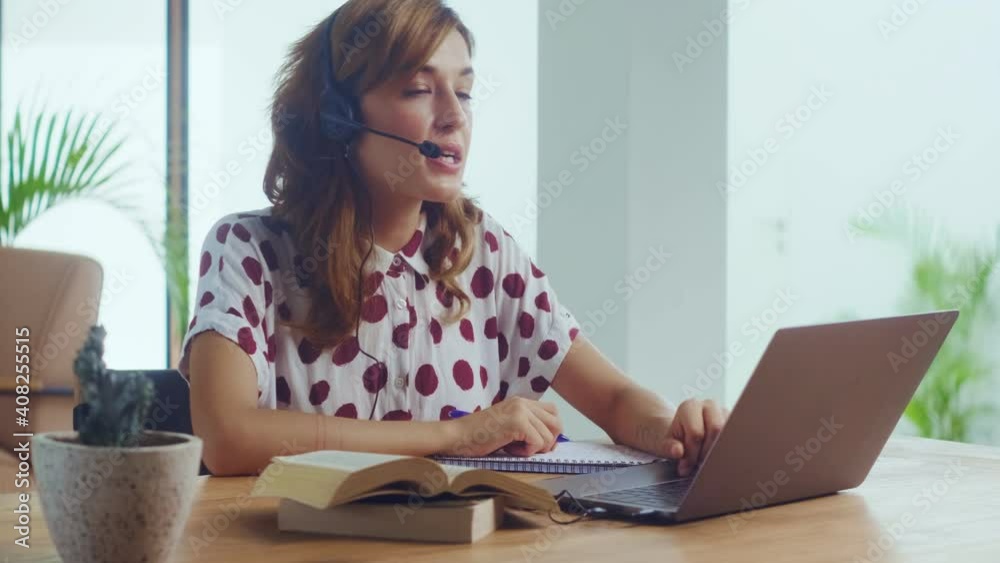 Female call center worker sitting desk focus on customer service member girl in headset looks at laptop screen write in notebook talk with client provide insurance information sell company product