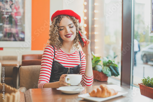 Happy young woman chatting and eating in european cafe