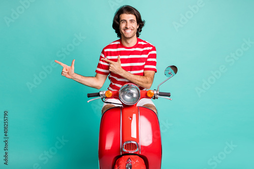 Portrait of nice content cheerful guy riding moped showing copy space advice ad isolated over bright green turquoise color background