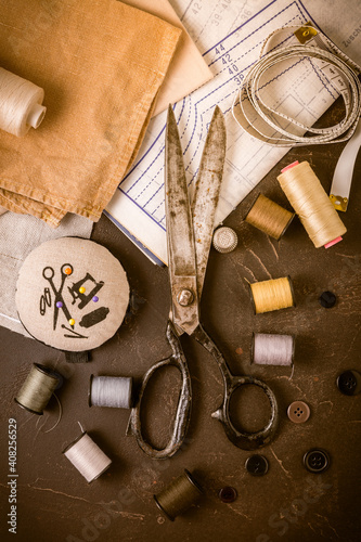 Sewing and craft tools - old scissors, bobbins with thread and needles on wooden table