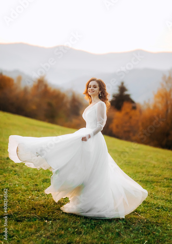 Young bride in wedding dress runing at sunset in the mountains