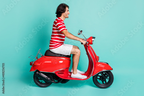 Profile side view portrait of handsome cheerful guy driving moped spending weekend isolated over bright green turquoise color background