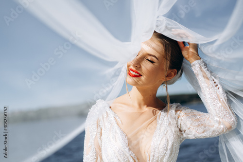 Portrait of a gentle bride in a wedding dress near the river on a sunny day
