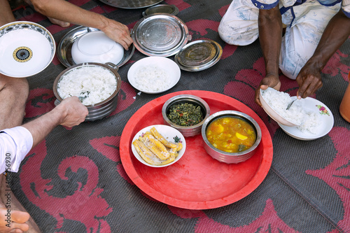 African food on the ground in african village house. People put food on the plate, visible hands. Homemade dishes ready to eat, view from above.
