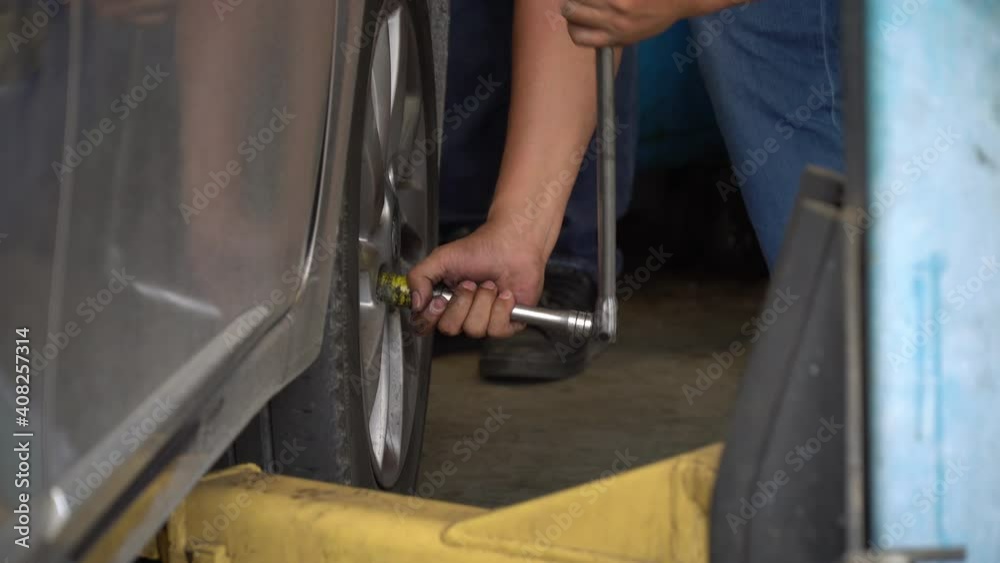 Mechanic using wheel wrench remove and changing wheel on car in workshop at car service . not removable loosen bolts. problem in garage Mechanic using wheel wrench remove and changing wheel on car in workshop at car service . not removable loosen bolts. problem in garage
