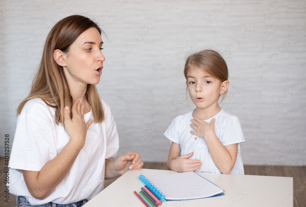 Young woman and little girl doing exercise for restructuring oral muscular phonetic targets. Young woman and little girl doing exercise for restructuring oral muscular phonetic targets.