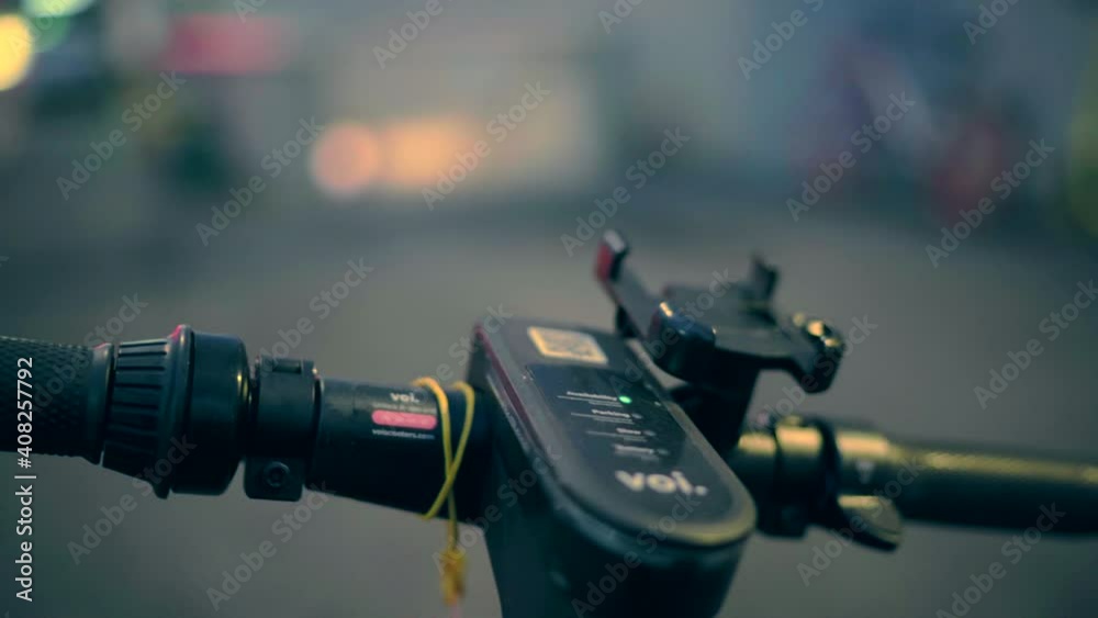 Electric kick scooter closeup in urban environment in the evening against blurred city background, scooter rental, freedom of movement. Electric bike in the city. Close up view. 4K video footage Electric kick scooter closeup in urban environment in the evening against blurred city background, scooter rental, freedom of movement. Electric bike in the city. Close up view. 4K video footage