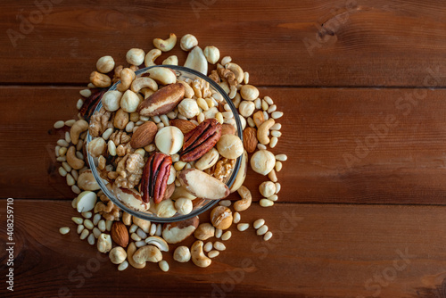 A mixture of nuts in a glass plate on a wooden table, a concept of healthy food, top view