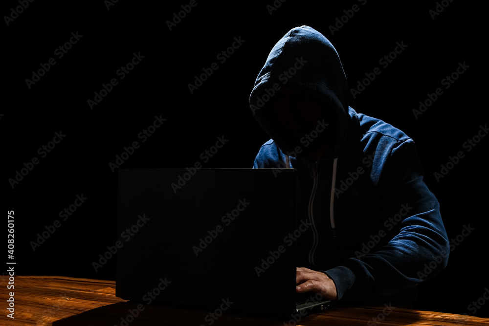 A Hacker with laptop sits at a table and abstract binary code. Business life threat virtual programs. A Hacker with laptop sits at a table and abstract binary code. Business life threat virtual programs.