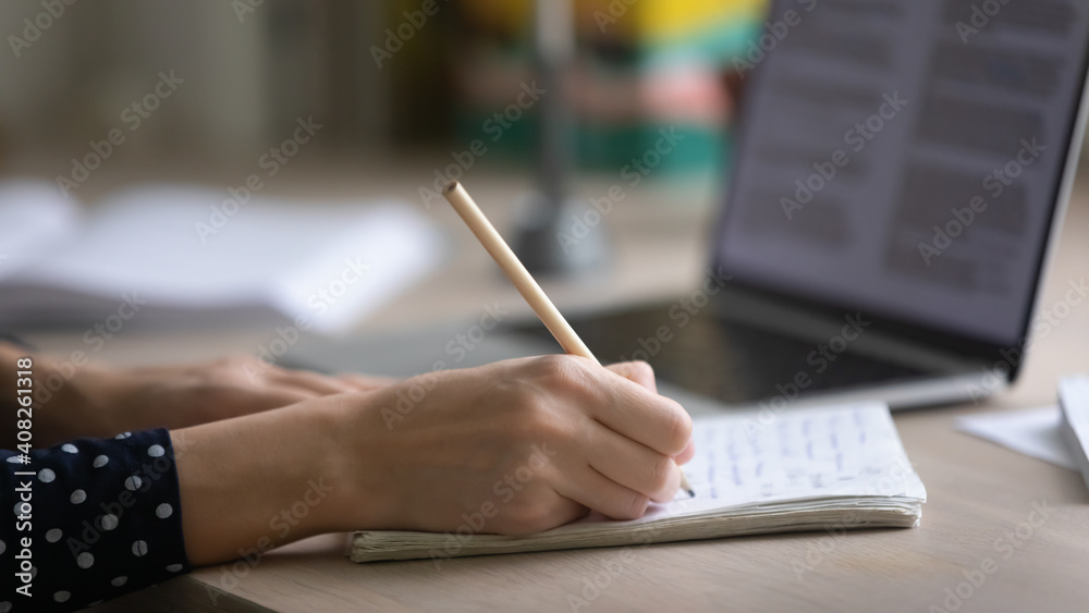 Remote working or learning. Close up of young woman hands making notes in paper copybook on desk by computer screen. Female student or pupil writing out information studying lecture lesson from home Remote working or learning. Close up of young woman hands making notes in paper copybook on desk by computer screen. Female student or pupil writing out information studying lecture lesson from home