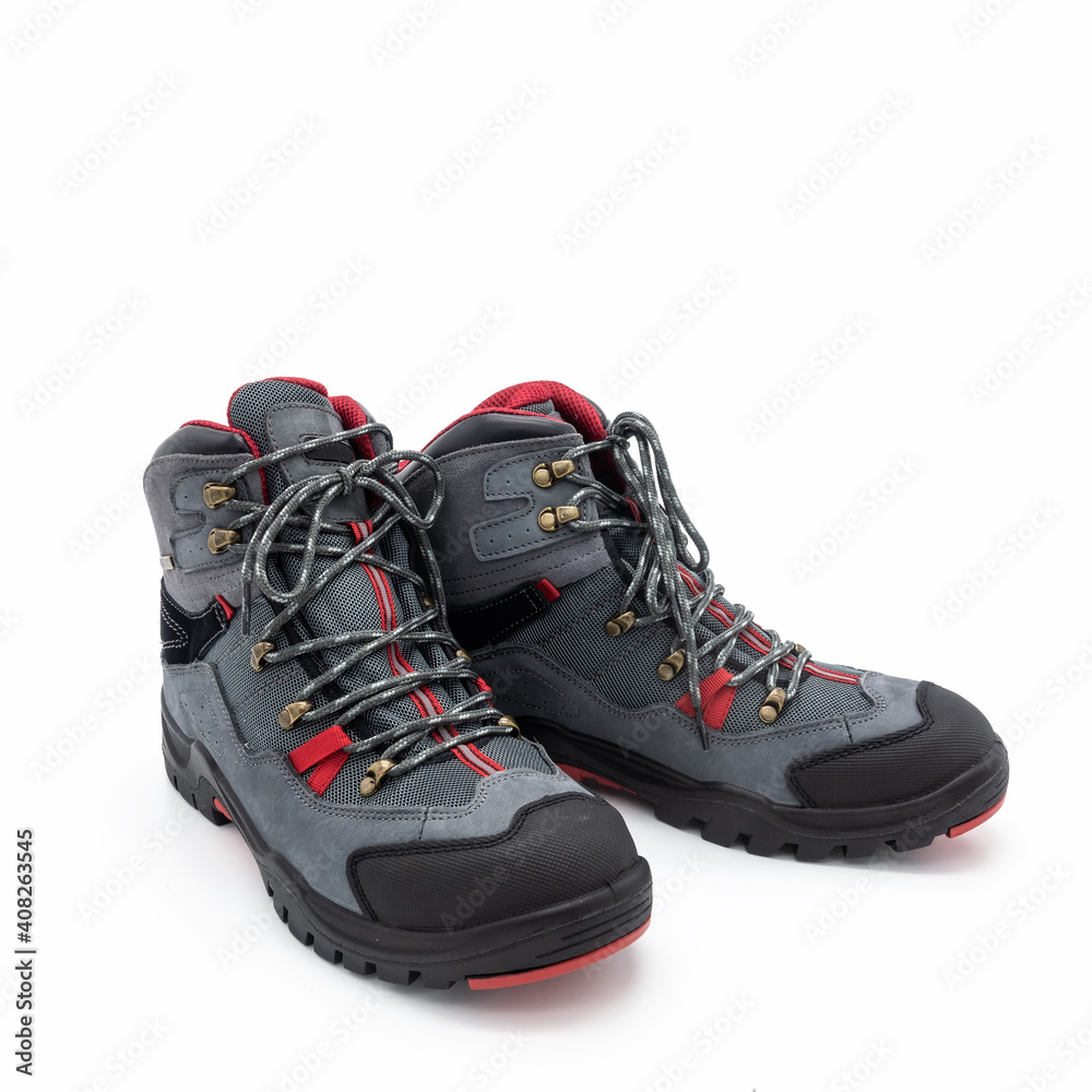 Trekking boots for men made of natural nubuck and synthetic mesh. Gray with red and black trim. Metal fittings. Grooved outsole. Isolated over white background. Trekking boots for men made of natural nubuck and synthetic mesh. Gray with red and black trim. Metal fittings. Grooved outsole. Isolated over white background.