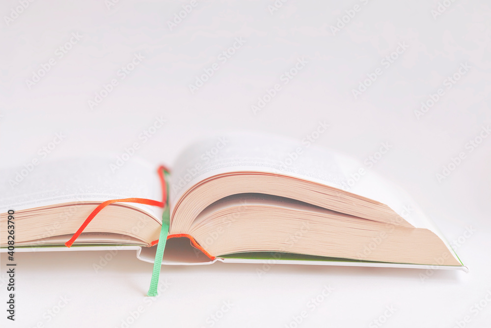 Fototapeta premium Open book close-up with colorful bookmarks on background of pink color tone. Selective focus