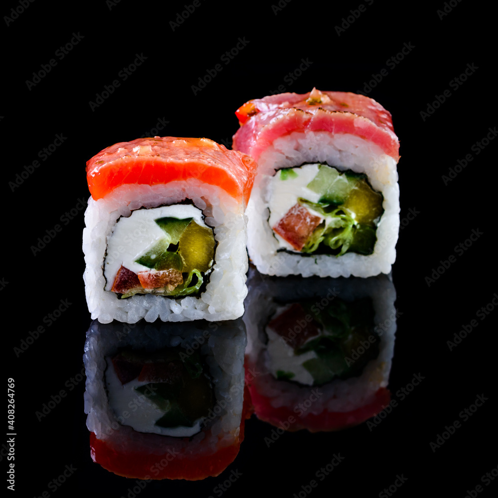 Concept of Asian cuisine. Two rolls of sushi with different fillings on a black background for Japanese menu. two sushi rolls couple isolated with reflection Concept of Asian cuisine. Two rolls of sushi with different fillings on a black background for Japanese menu. two sushi rolls couple isolated with reflection