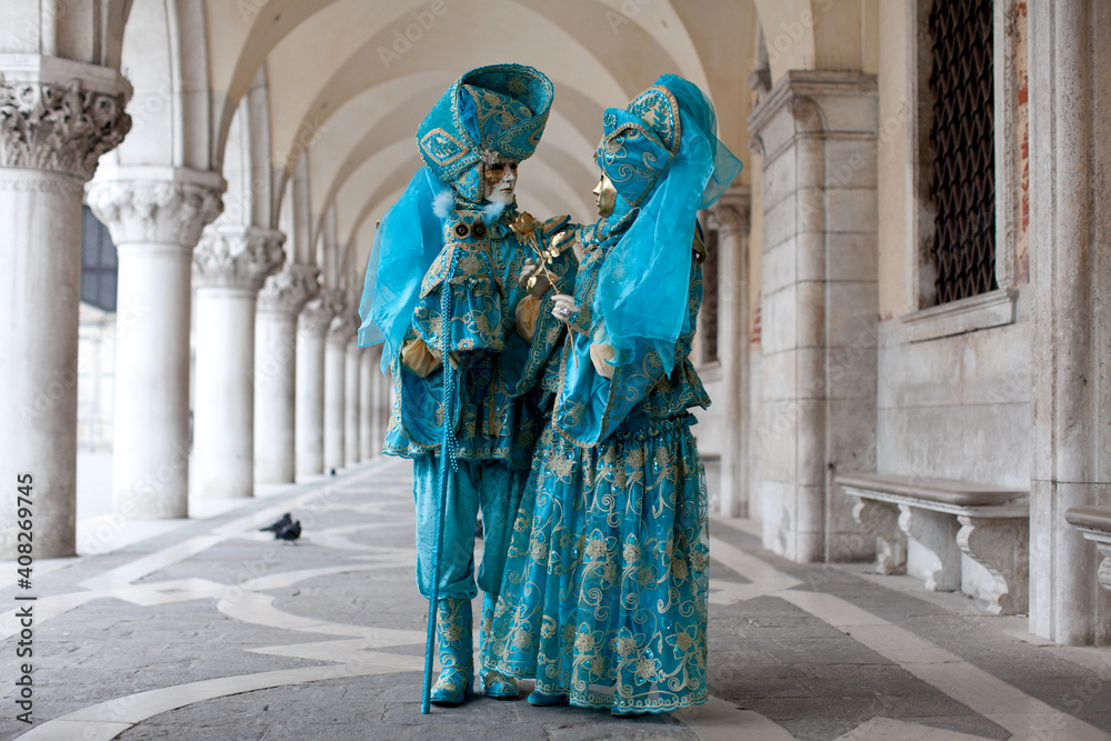 Masked couple in ornate costume at the the Venetian masquerade stands near St. Mark's Square in Venice Masked couple in ornate costume at the the Venetian masquerade stands near St. Mark's Square in Venice