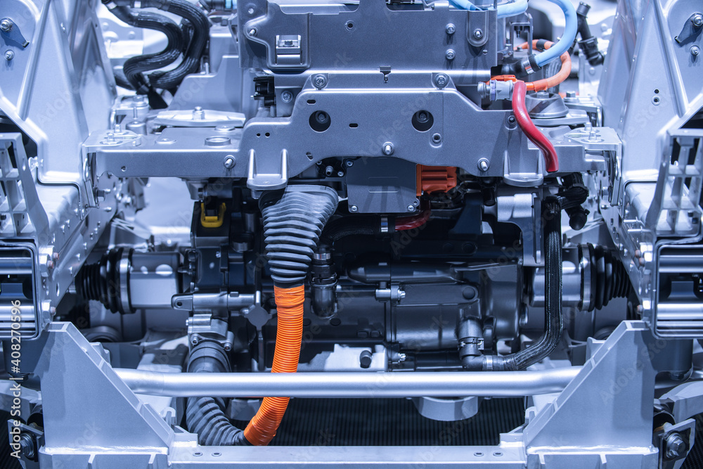 Chassis of the electric car with powertrain and power connections closeup. Blue toned. EV car drivetrain at maintenance.