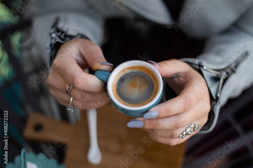 blue cup in female groomed hands with manicure and rings at work