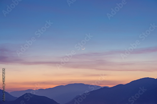 New moon over mountains silhouette
