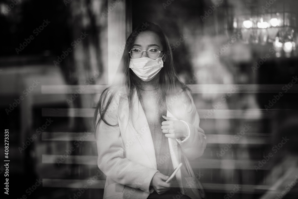 Young Asian businesswoman with mask using phone and sitting with distance outside the coffee shop Young Asian businesswoman with mask using phone and sitting with distance outside the coffee shop