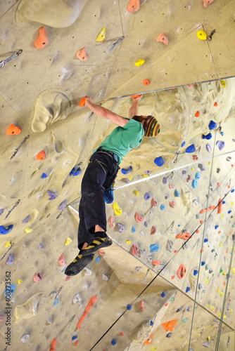young sporty man bouldering in a climbing hall - indoor sports