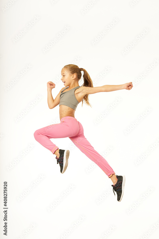Adorable sporty girl jumping against white background