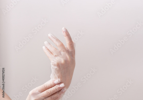 Feminine hands in transparent vinyl gloves.