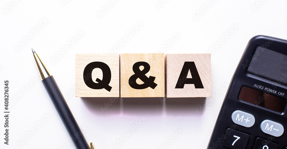 The word Q AND A QUESTIONS AND ANSWERS is written on wooden cubes between a pen and a calculator on a light background. The word Q AND A QUESTIONS AND ANSWERS is written on wooden cubes between a pen and a calculator on a light background.