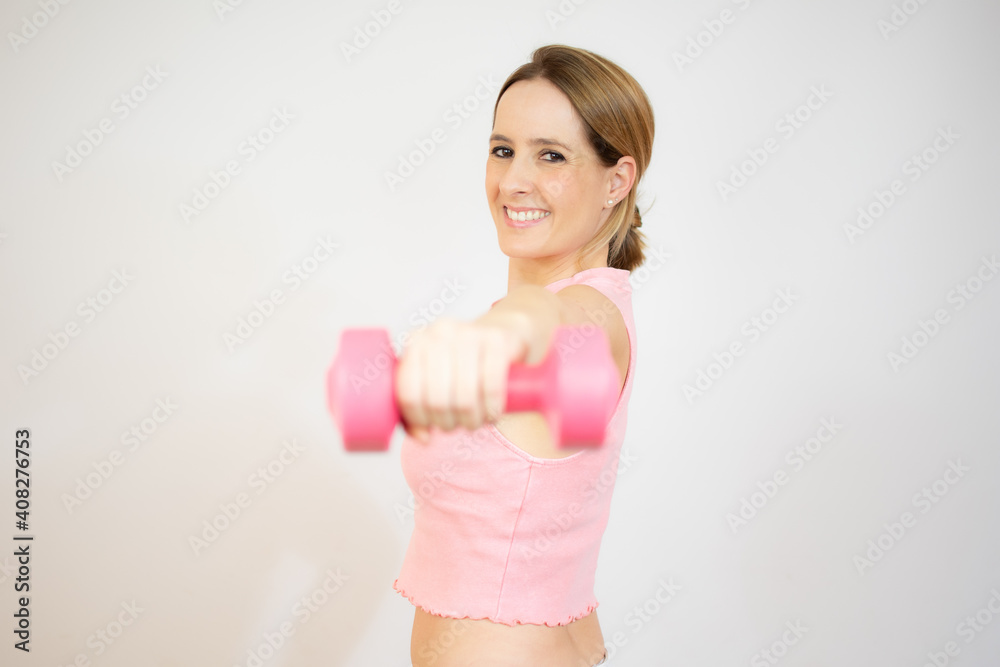 Smiling blonde woman holding dumbbell over white background. Smiling blonde woman holding dumbbell over white background.