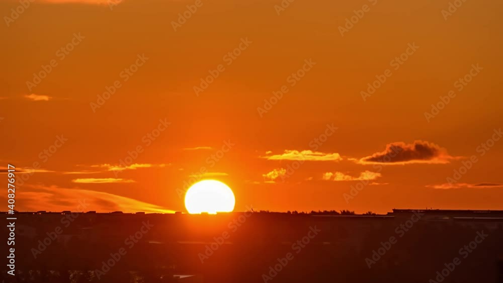 Time-lapse of sunrise and silhouettes of city, rising sun and floating clouds in orange sky Time-lapse of sunrise and silhouettes of city, rising sun and floating clouds in orange sky