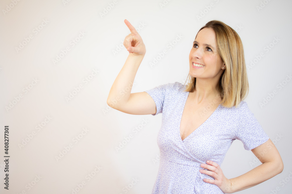 Smiling woman pointing up with index finger standing over white background. Smiling woman pointing up with index finger standing over white background.