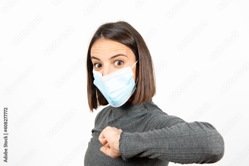 A woman greeting with her elbow while wearing a medical face mask. Healthcare during Coronavirus pandemic concept. A woman greeting with her elbow while wearing a medical face mask. Healthcare during Coronavirus pandemic concept.