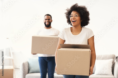 Excited African Couple Carrying Moving Boxes Entering Own Home