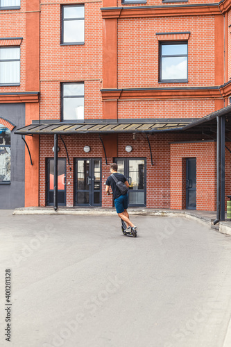 A young man rides around the city on an electric scooter. Vertical photo. Ecological transport © _nastassia