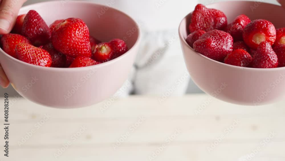 close up female hands takes two pink bowls with clean ripe strawberries and shows to camera. health and organic vegan and vegetarian food concept close up female hands takes two pink bowls with clean ripe strawberries and shows to camera. health and organic vegan and vegetarian food concept
