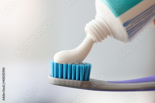 White toothpaste is applied to toothbrush closeup