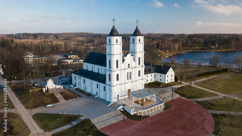 Top drone view of Aglona Roman Catholic Basilica of the Assumption of the Blessed Virgin Mary in Latvia. Forest and lake.
