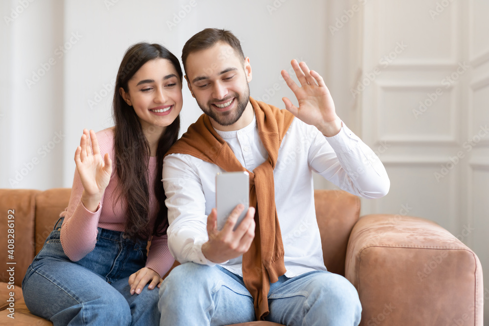 Arab couple making video call via phone sitting at home Arab couple making video call via phone sitting at home