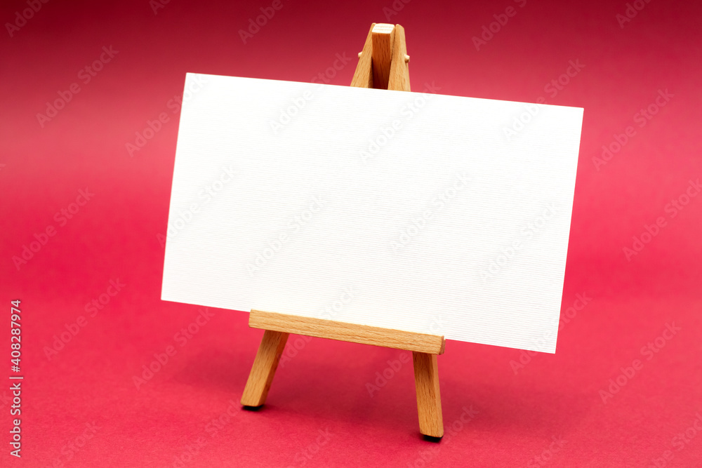 White sheet on wooden easel, isolated on red background. White sheet on wooden easel, isolated on red background.