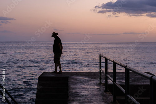 lonely man standing in the pier during sunset