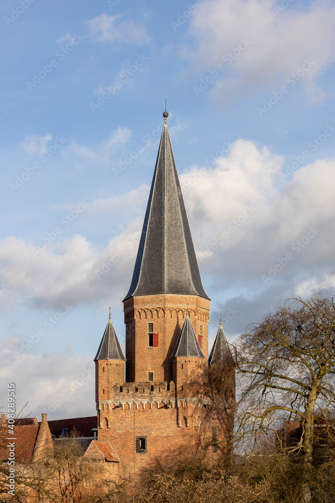 Soft blue sky and fluffy clouds behind Drogenapstoren rooftop rising above medieval Hanseatic city Zutphen in The Netherlands