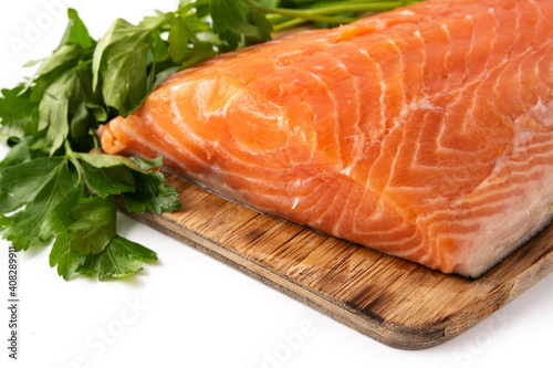 Raw salmon fillet and parsley on cutting board isolated on white background
