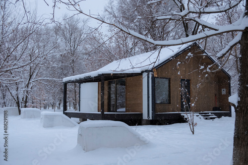 Cozy modular simple house in winter forest. Hygge lifestyle concept. Winter season. Eco-friendly prefabricated quick-build house. © Adil