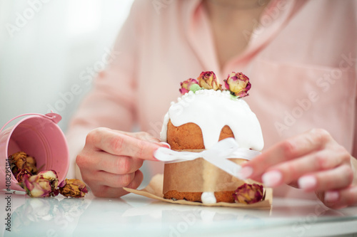 Woman hands holding traditional russian easter cake on table. The decorarion of kulich are the flower are eating on spring holiday photo