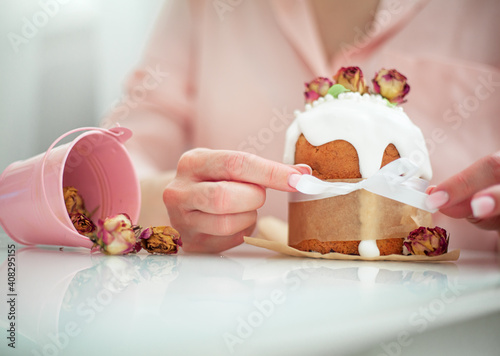 Woman hands holding traditional russian easter cake on table. The decorarion of kulich are the flower are eating on spring holiday photo